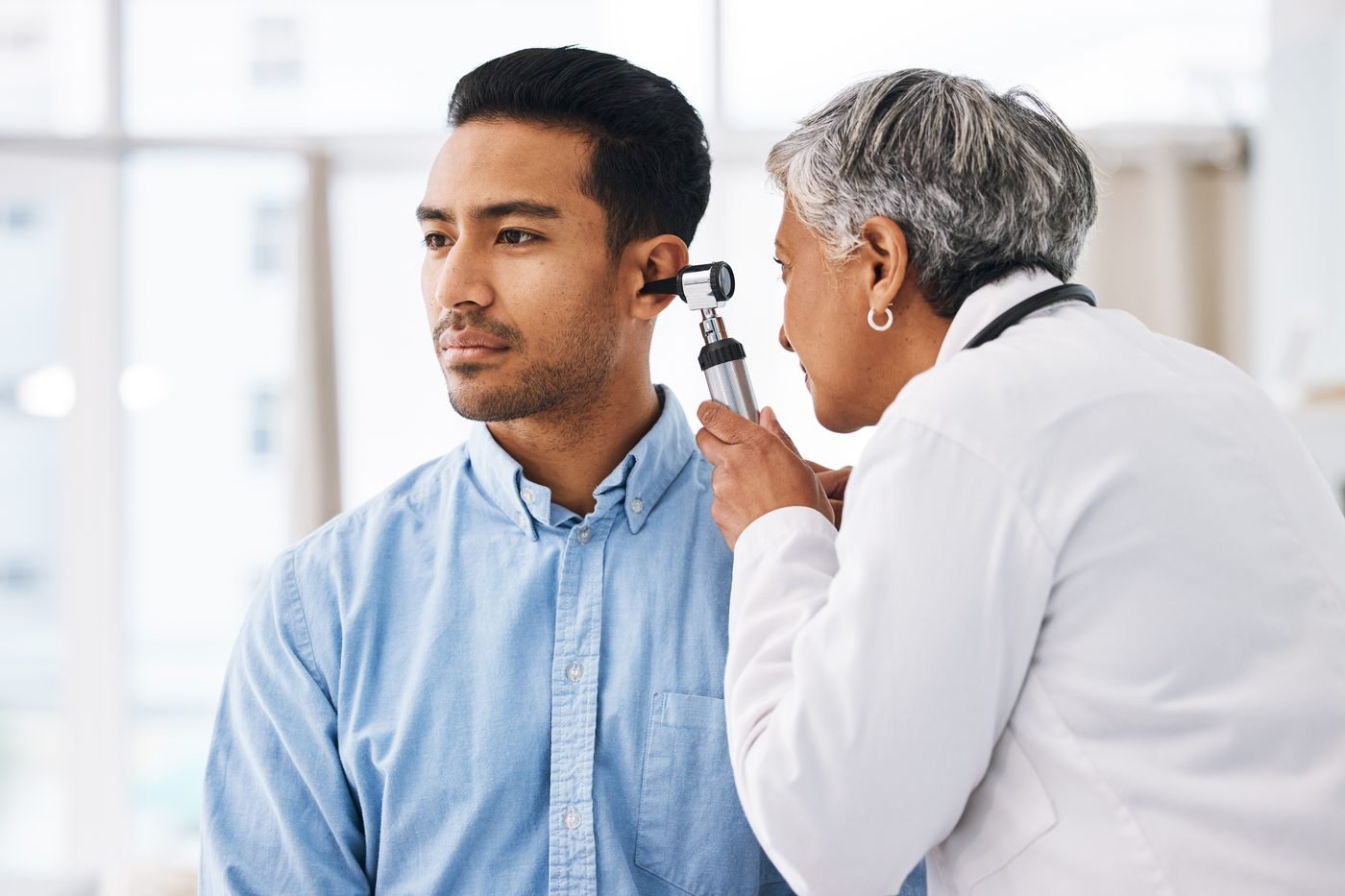 An audiologist examining a patient's ear with an otoscope
